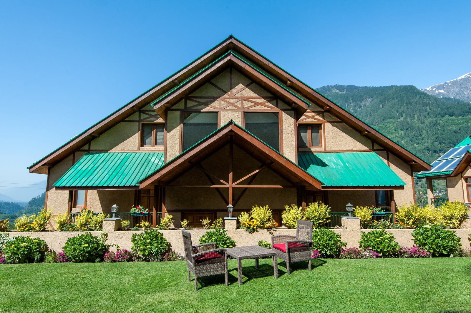 A villa behind flower beds with the valley beyond